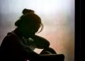 Vintage filtered on silhouette of depressed girl sitting on the window