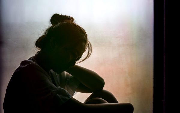 Vintage filtered on silhouette of depressed girl sitting on the window